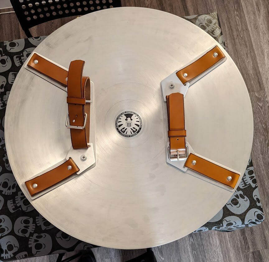Back of a replica Captain America shield, showing leather straps and aluminum brackets cut by SendCutSend